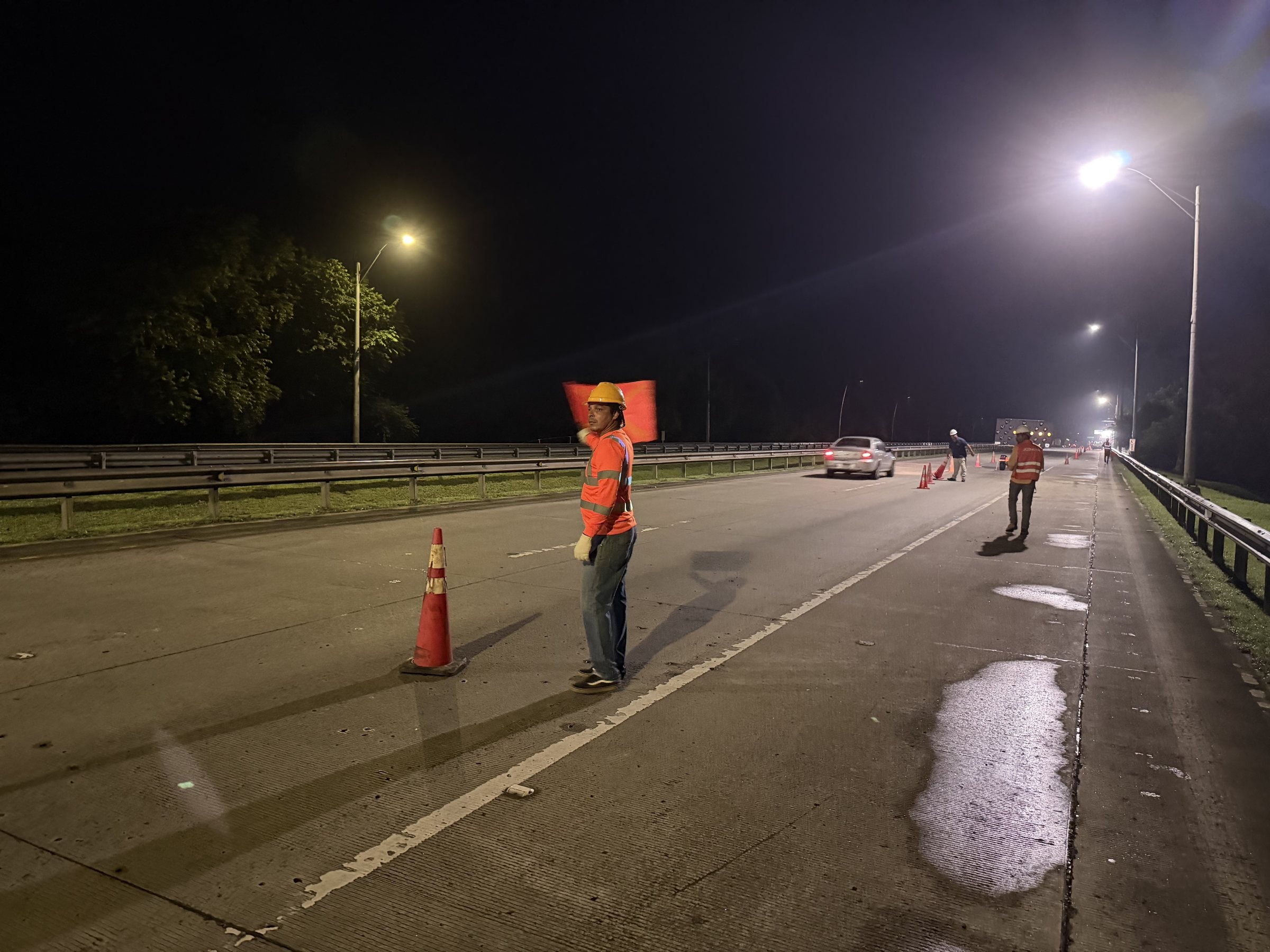 Highway lane closure with cones, traffic control crew and lighting at night
