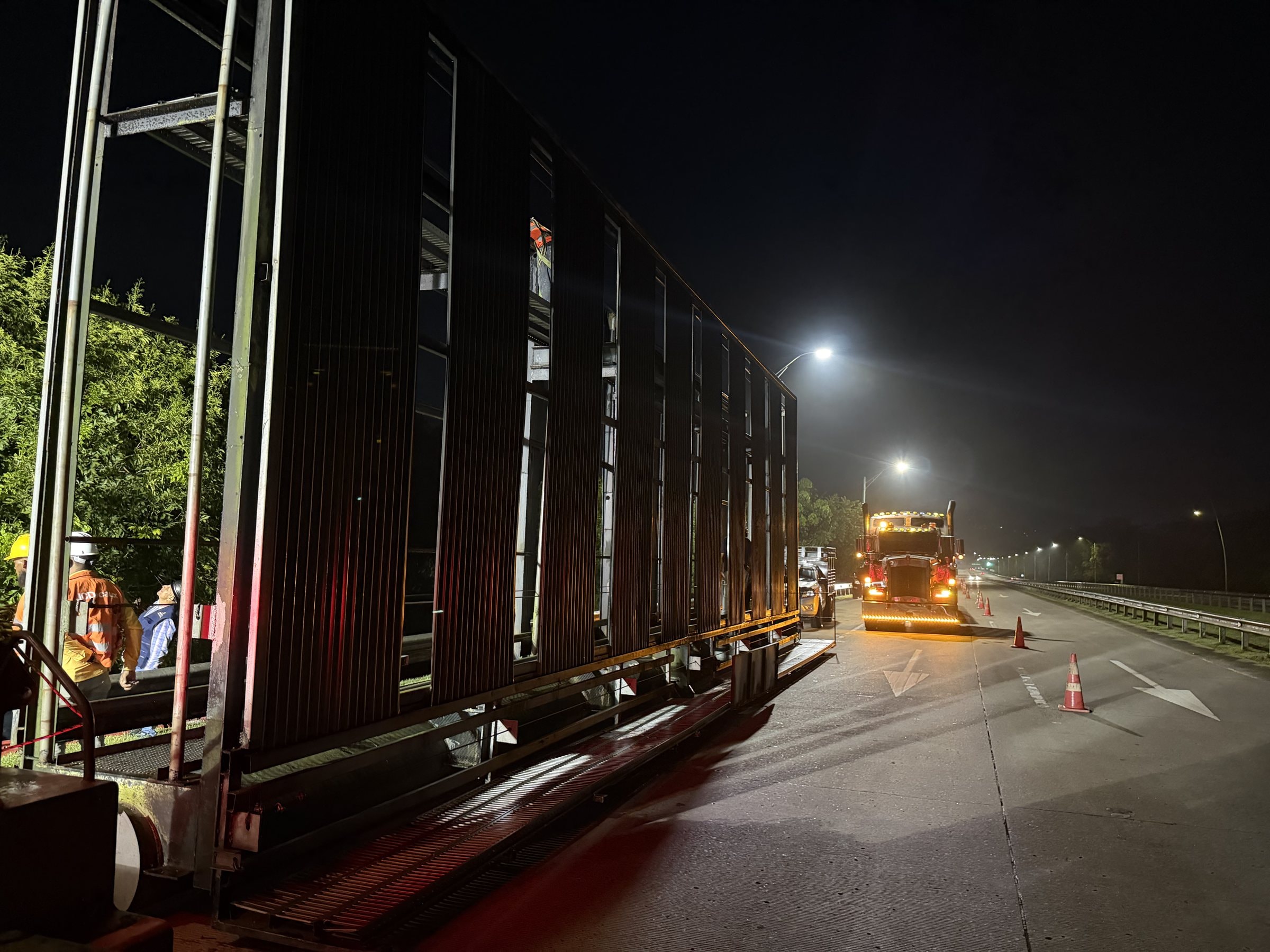 Dismantled billboard structure loaded onto a truck on a cleared highway at night